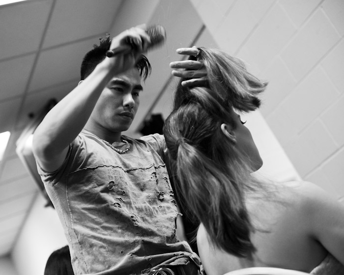 A hairstylist works on one of the models before the show